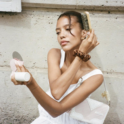 model looking at chantilly compact mirror while brushing hair