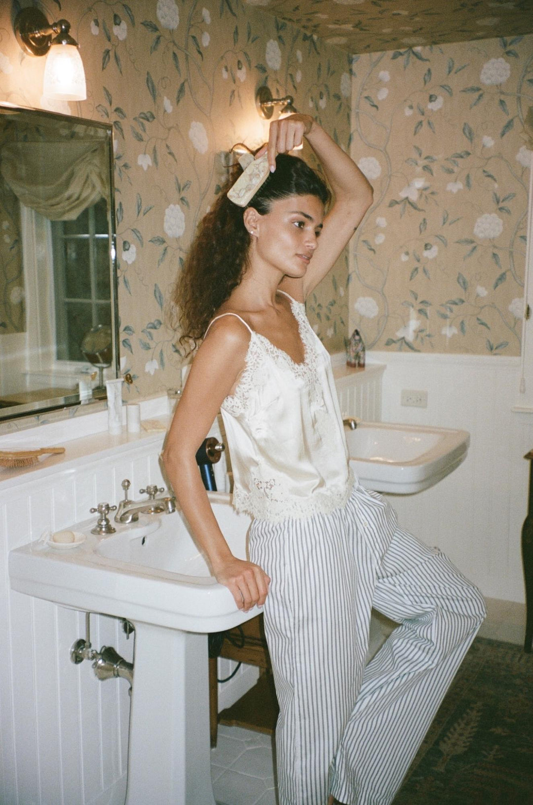 model leaning on bathroom sink while brushing hair with mini boar brush in chantilly