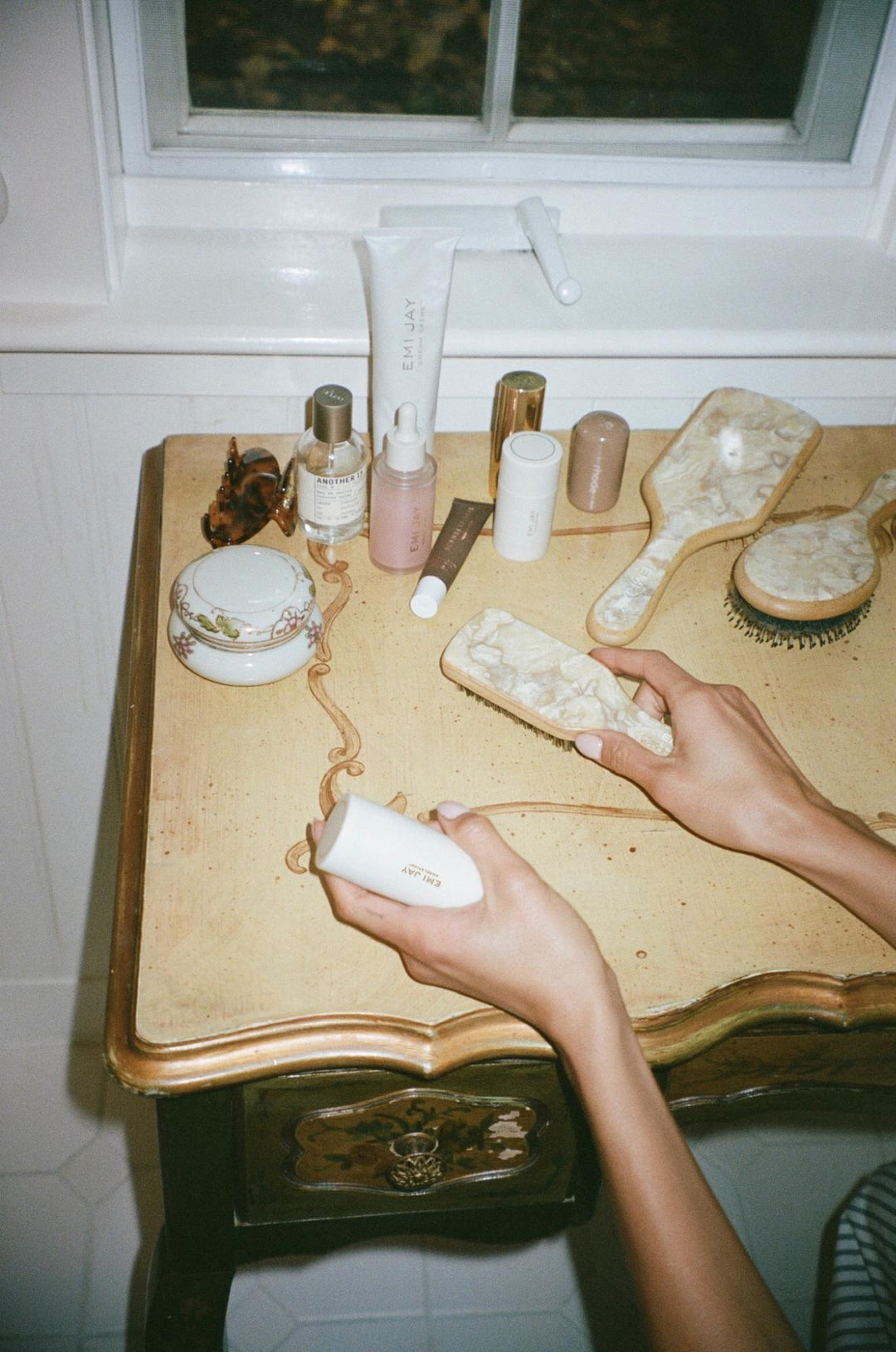 model holding angelstick while setting mini boar brush on table with assorted hair care, styling tools, and accessories