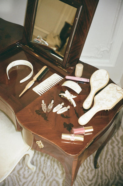 assorted chantilly hair brushes and accessories on vanity next to mirror