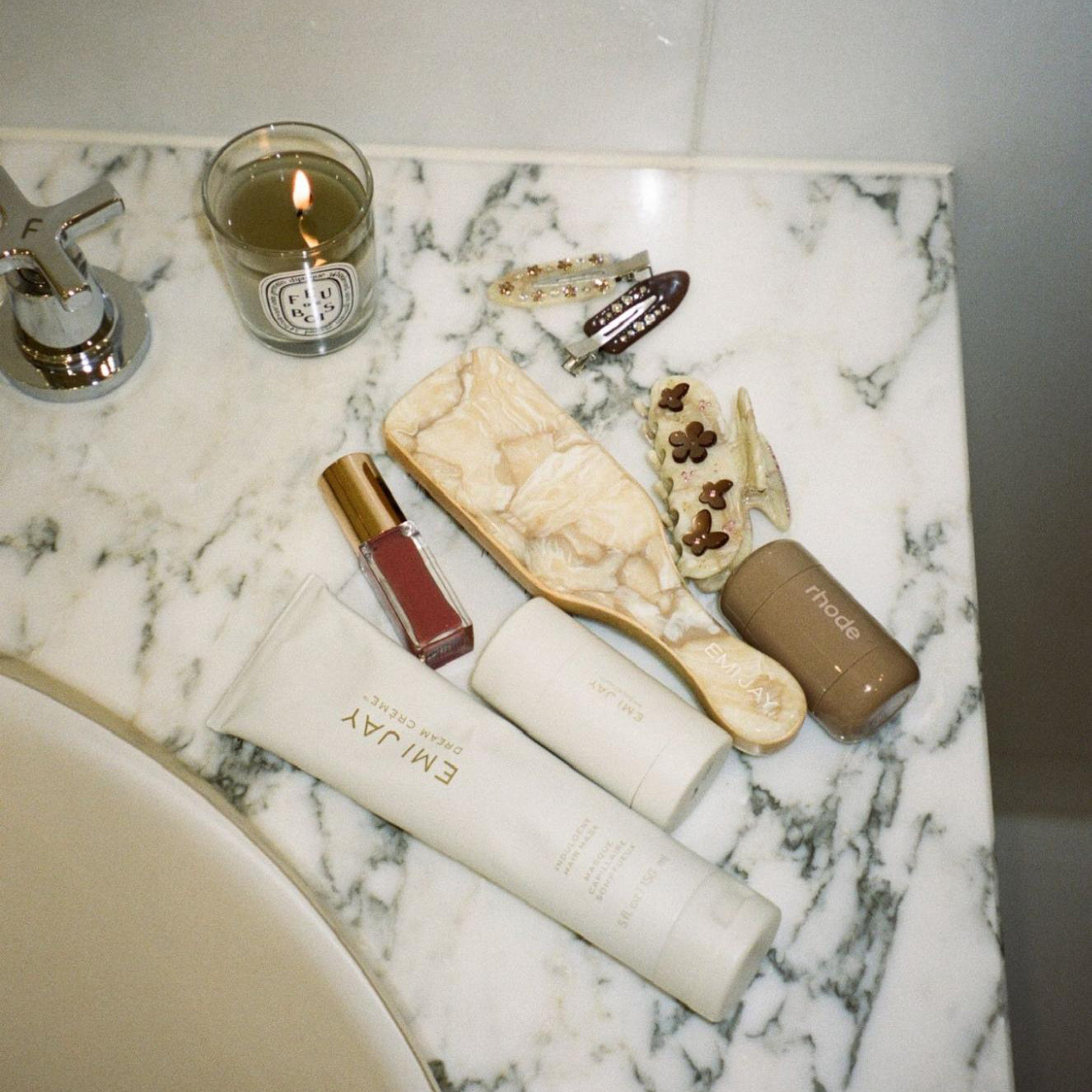 Mini Boar Bristle Brush in Chantilly on bathroom sink with assorted accessories and candle