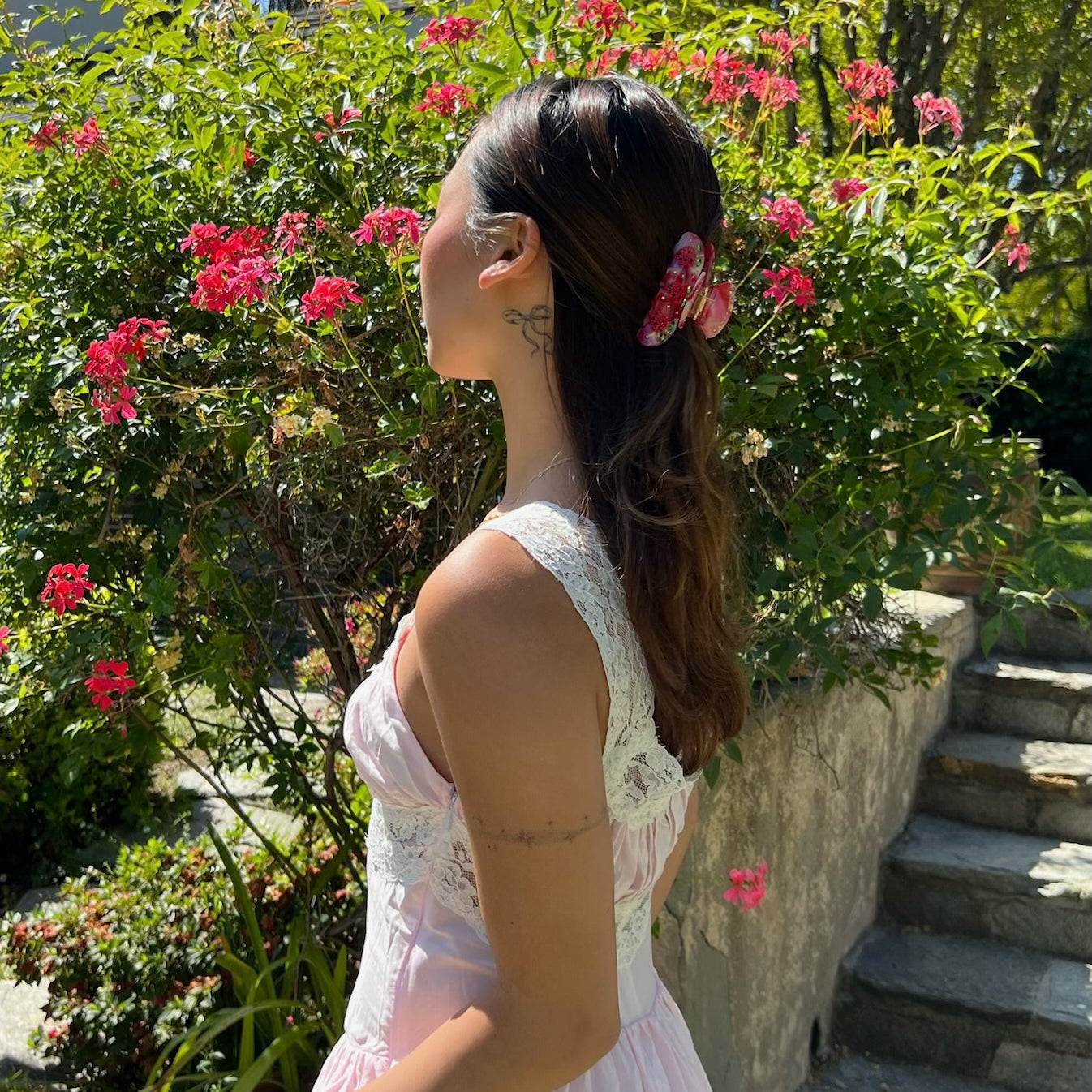 model standing in front of flowers with Sweetheart Clip in Strawberry Glow in hair